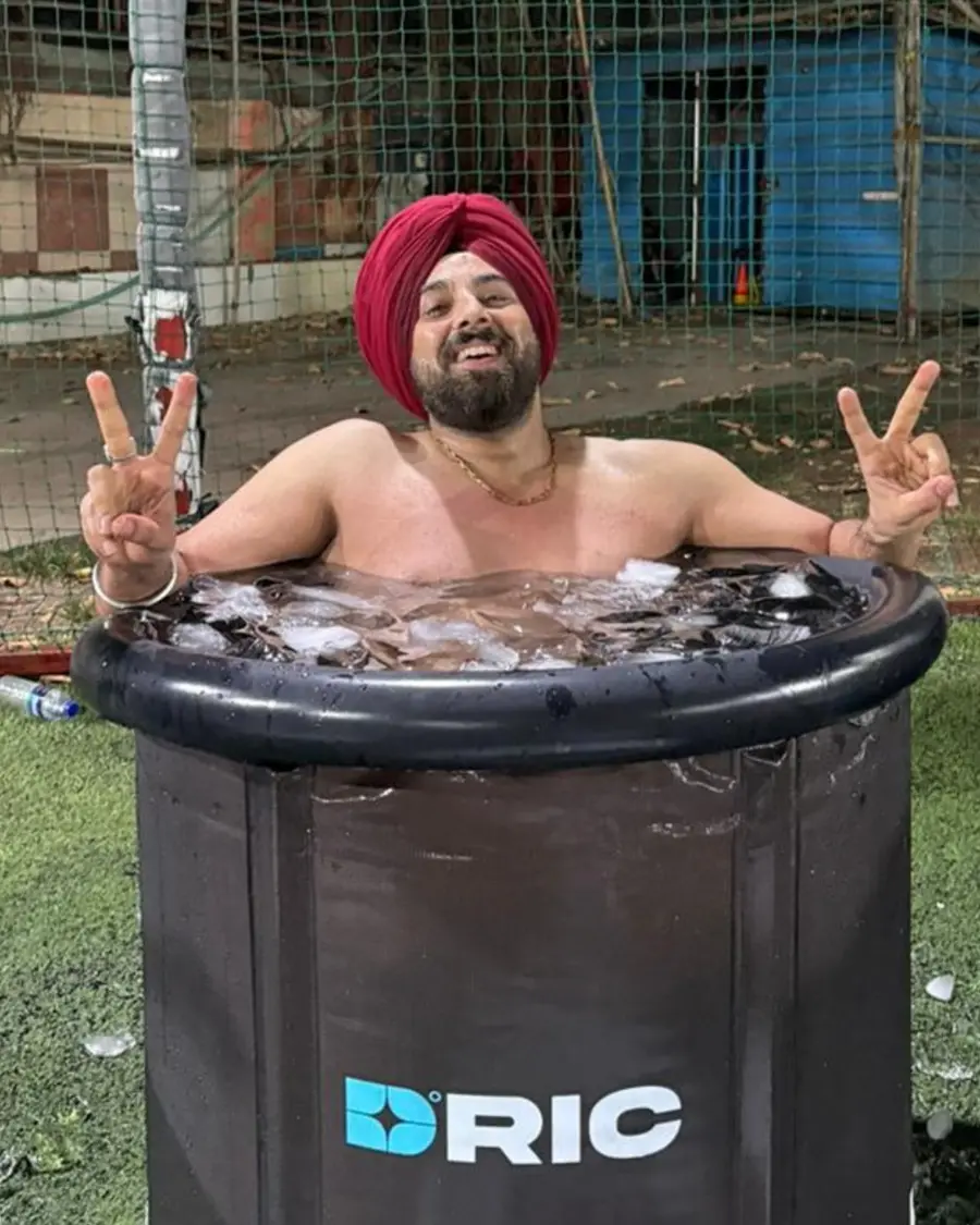 A participant in a red turban flashing peace signs from the ice